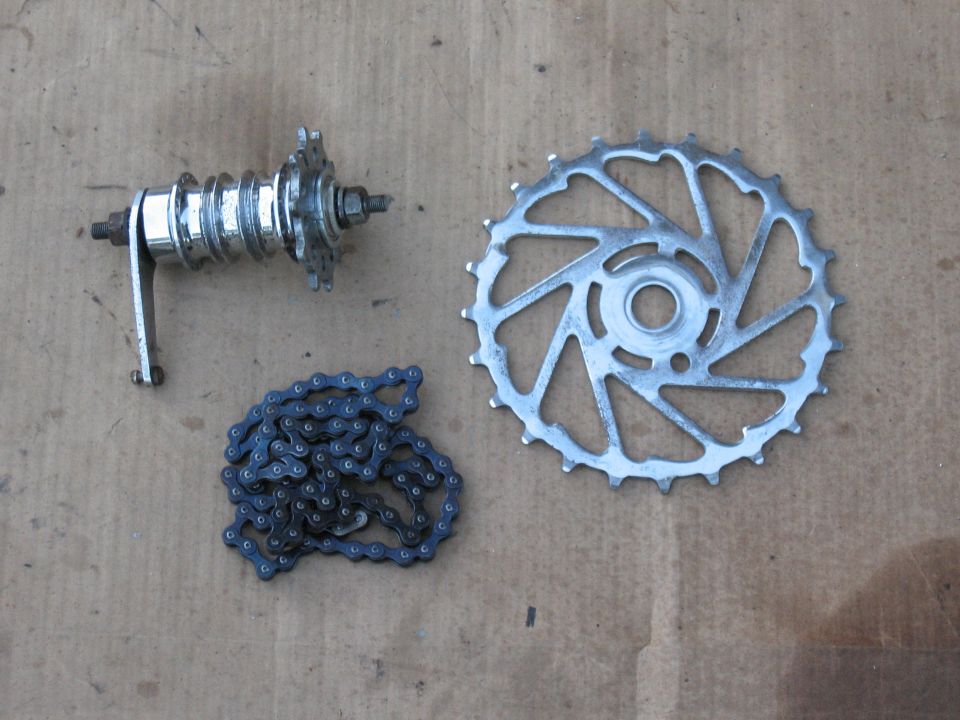 Bicycle chain, hub, and sprocket laid out on a cardboard surface