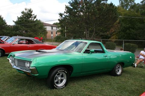 1971 Ford Ranchero - Green Ford Ranchero pickup truck with black hood stripe, parked on grass next to a red car.