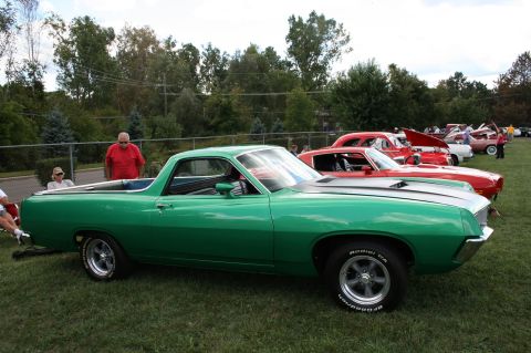 1971 Ford Ranchero - A green coupe utility vehicle is parked on a grassy field alongside other cars at an outdoor event.