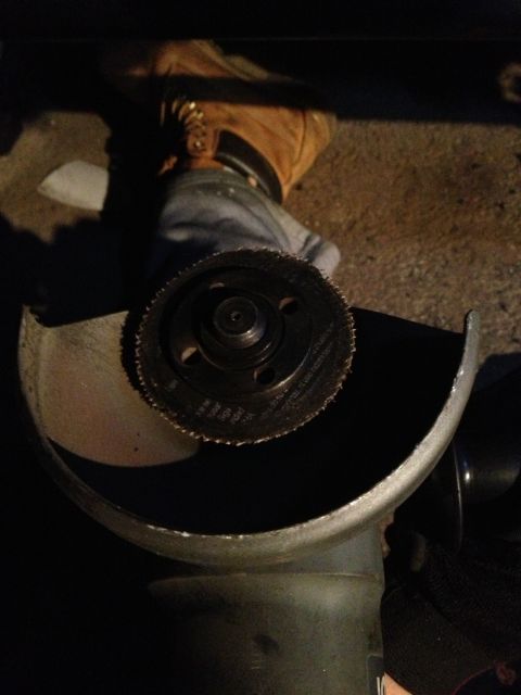 1996 Ford F-150 - An angle grinder with a cutting disc is shown, with a person's hand and boot in the background.