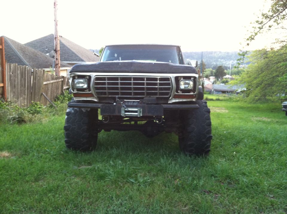 Front view of lifted patina Ford Bronco with winch and tall military-tread tires