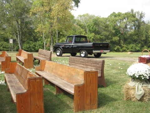 1966 Ford F-100 - A vintage black pickup truck is parked outdoors on a grassy area with wooden benches.