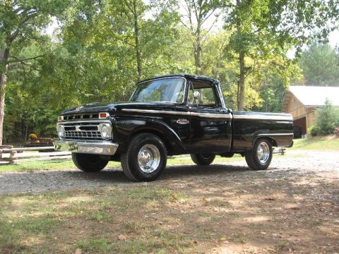 1966 Ford F-100 - This black 1966 Ford F-100 pickup truck features distinctive chrome accents and is captured in a three-quarter front view.