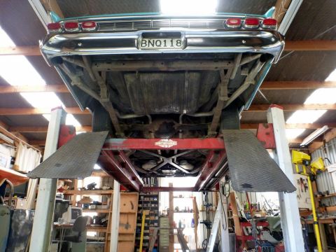 1964 Mercury Monterey - The rear underside of a vintage automobile is shown elevated on a hydraulic lift in a workshop.