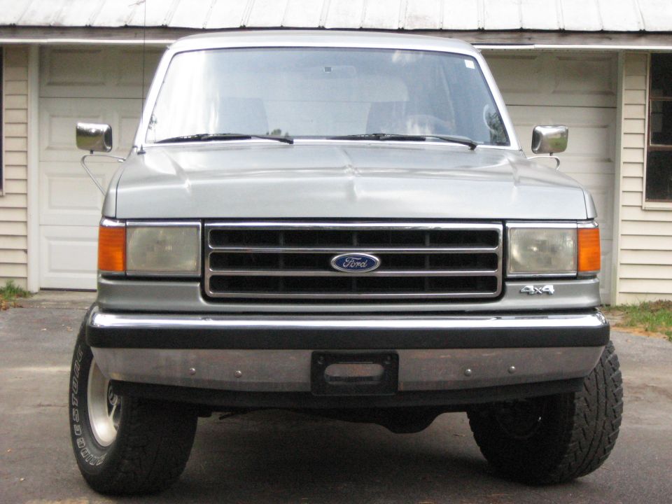 Silver Ford Bronco front view, parked in front of a garage
