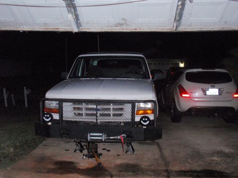 1995 Ford Bronco - A white Ford truck, possibly from the early 1990s, is parked in a garage with its front end raised on jacks.