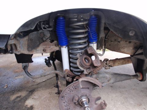 1995 Ford Bronco - Close-up view of the front suspension system, prominent coil springs and shocks with blue protective boots.