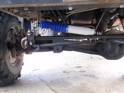 1995 Ford Bronco - Undercarriage view shows steering components and a shock absorber with blue bellows.