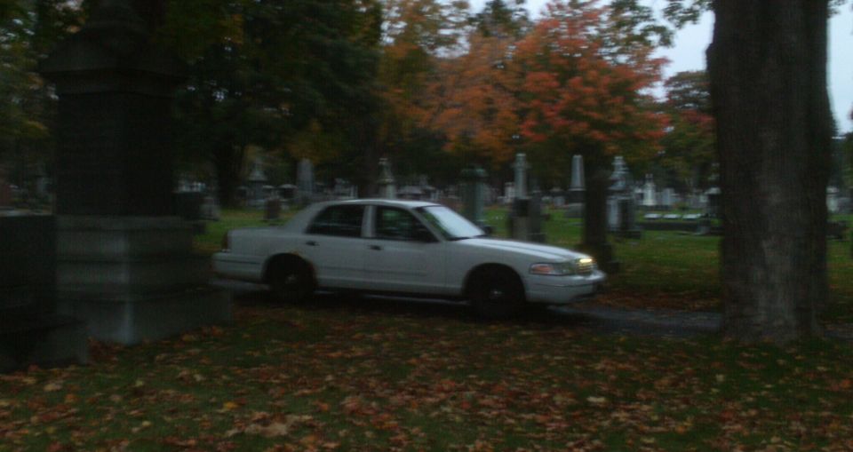White 1998 Ford Crown Victoria parked in a cemetery with fall foliage