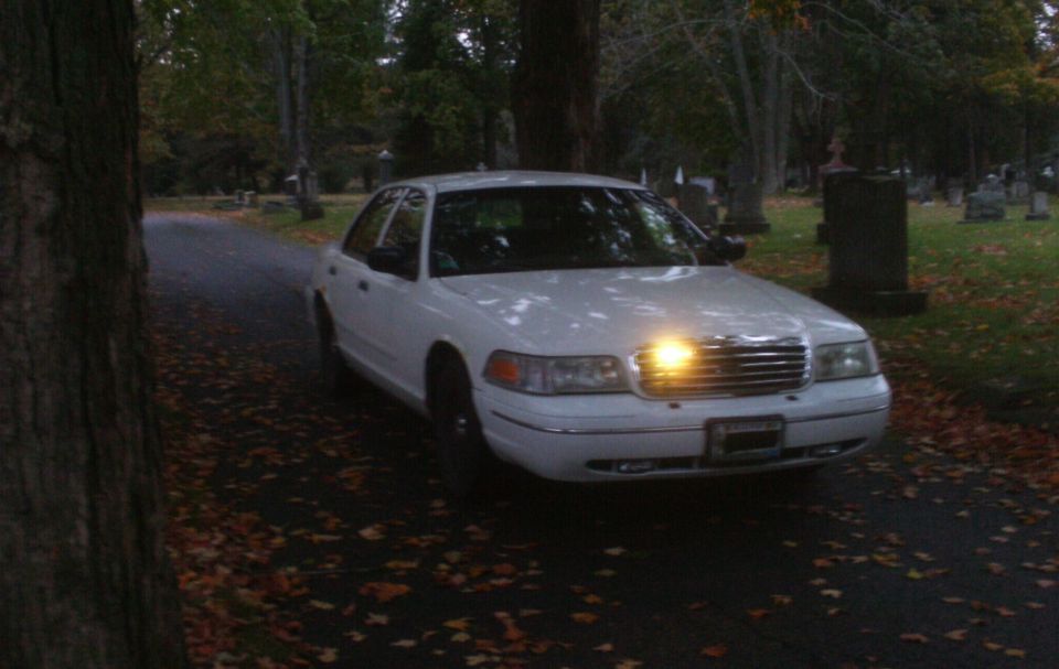 White 1998 Ford Crown Victoria parked on a road in a cemetery, front 3/4 view