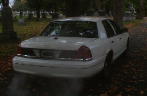 1998 Ford Crown Victoria - Rear view of a white 1998 Ford Crown Victoria parked among gravestones.