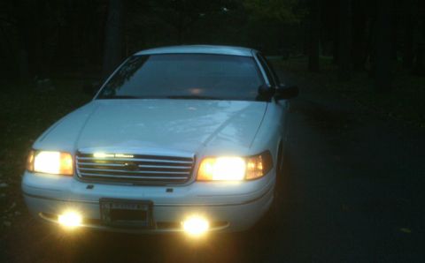 1998 Ford Crown Victoria - Front view of a white 1998 Ford Crown Victoria, illuminated by its headlights and fog lights.
