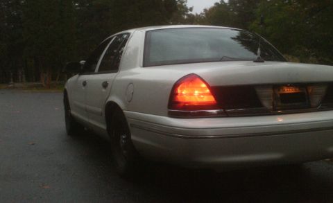 1998 Ford Crown Victoria - Rear view of a white 1998 Ford Crown Victoria parked on a wet road.