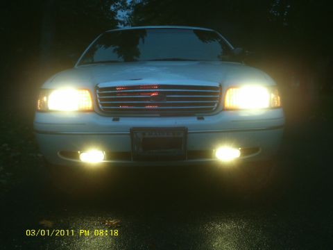 1998 Ford Crown Victoria - The front of a 1998 Ford Crown Victoria is illuminated by its headlights and fog lights at night.