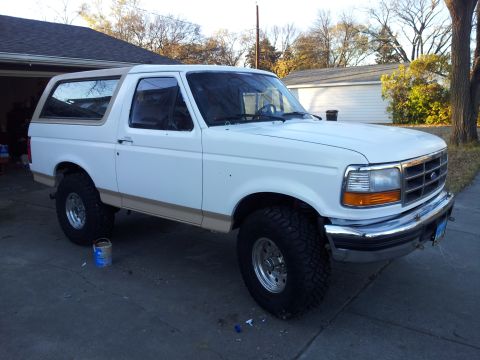 1996 Ford Bronco - White 1996 Ford Bronco with tan trim and aftermarket wheels sits in a driveway.