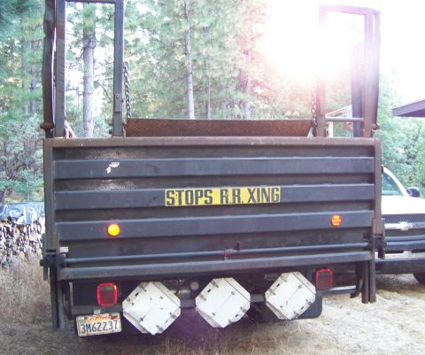 1994 Ford F-150 - The rear of a flatbed truck is shown, a railroad crossing warning sign and a second vehicle partially visible to the right.