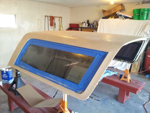 1996 Ford Bronco - A Ford Bronco hardtop is shown with blue painter's tape around the window, resting on jack stands in a garage.