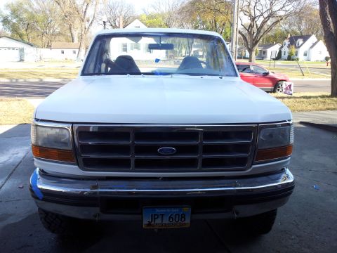 1996 Ford Bronco - Front view of a white 1992 Ford Bronco, with a red car visible in the background.
