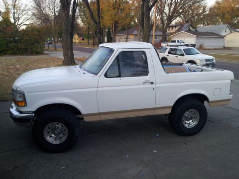 1996 Ford Bronco - Side view of a lifted 1996 Ford Bronco with tan trim and aftermarket wheels.