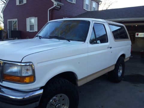 1996 Ford Bronco - A white Ford Bronco is parked in front of a house and garage, viewed from the front-right side.