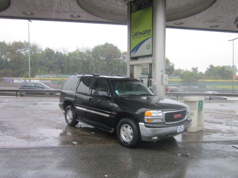 1991 Ford LTD Crown Victoria - A black GMC Yukon SUV is parked at a gas station on a rainy day.