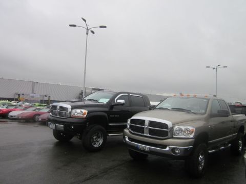 1991 Ford LTD Crown Victoria - Two Dodge Ram trucks are parked side-by-side in an outdoor lot under a cloudy sky.