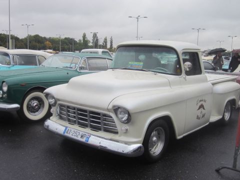 1991 Ford LTD Crown Victoria - A classic white pickup truck is parked next to a green vintage car on a cloudy day.
