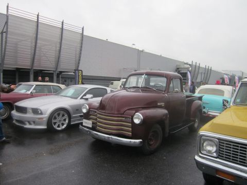 1991 Ford LTD Crown Victoria - A maroon pickup truck is parked in a lot with several other vehicles, including a silver Mustang and a light blue convertible.