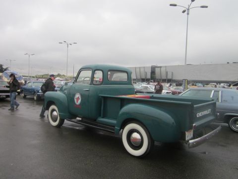 1991 Ford LTD Crown Victoria - A green Chevrolet pickup truck is parked in a lot with other vehicles under a cloudy sky.
