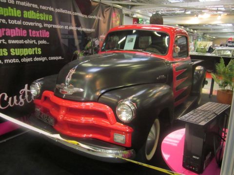 1991 Ford LTD Crown Victoria - A classic Chevrolet pickup truck with a two-tone black and red paint scheme is displayed indoors.
