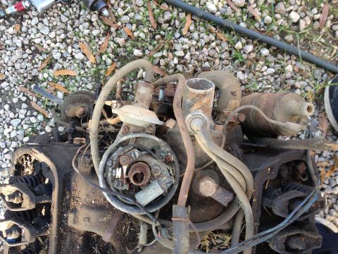 1987 Ford Ranger - Close-up of a disassembled engine part, possibly a distributor, lying on gravel.