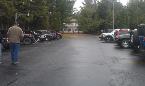 1979 Ford Bronco - A group of SUVs are parked in a lot on a cloudy day, with a large building visible behind them.