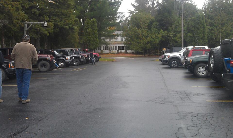 Several SUVs parked in a lot with a building and trees in the background