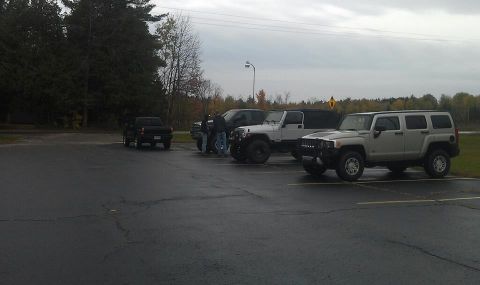 1979 Ford Bronco - Several SUVs and a pickup truck are parked in an outdoor lot under an overcast sky.