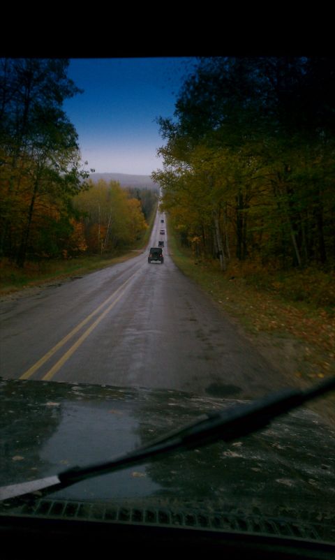 1979 Ford Bronco - A line of vehicles travels down a wet road during the fall season.