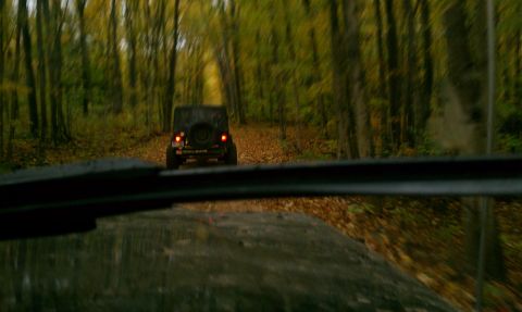1979 Ford Bronco - A Jeep follows another vehicle down a wooded path during autumn.