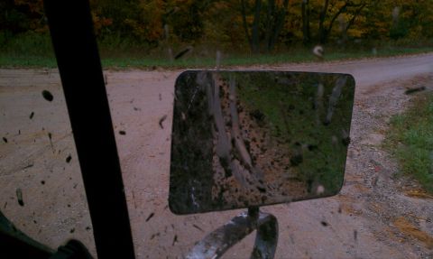 1979 Ford Bronco - View from inside a vehicle looking at a side mirror reflecting a muddy road.