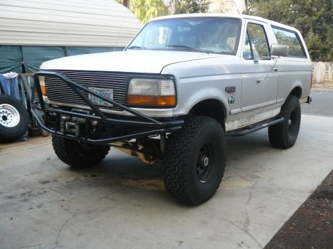 1994 Ford Bronco - This silver Ford Bronco features a custom front bumper and winch, lifted suspension, and large off-road tires.