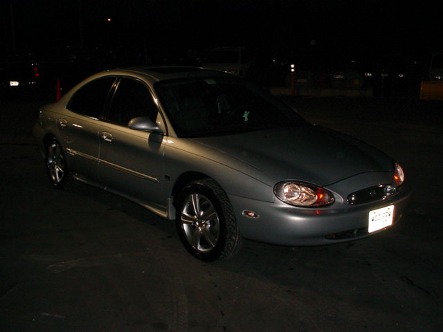 Silver sedan parked at night. License plate is visible