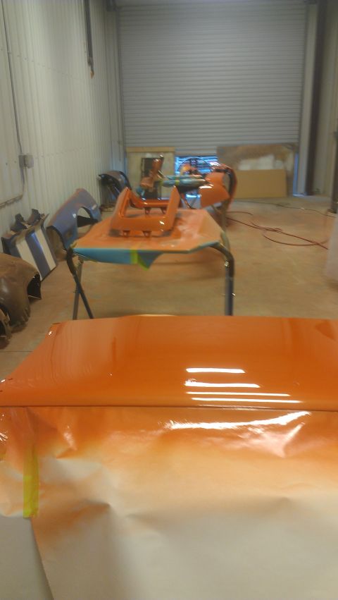 1973 Chevrolet Camaro - Car parts are being painted orange in a workshop setting.