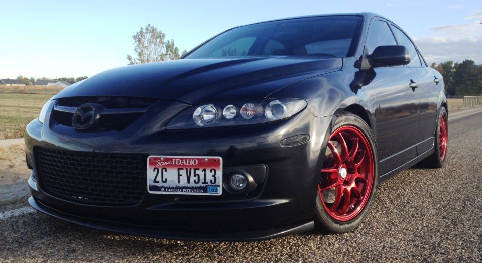 Black Mazda 6 sedan with red rims parked on a gravel road