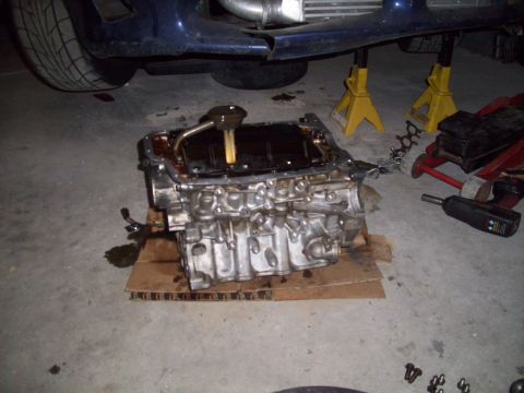 1995 Ford Probe - Engine block removed from a vehicle, resting on cardboard with oil leaks visible on the floor.