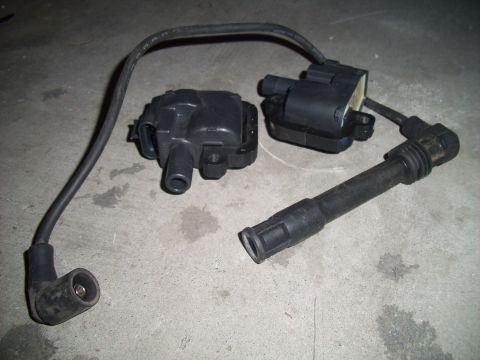 1995 Ford Probe - Ignition coils and a spark plug wire are laid out on a concrete floor.