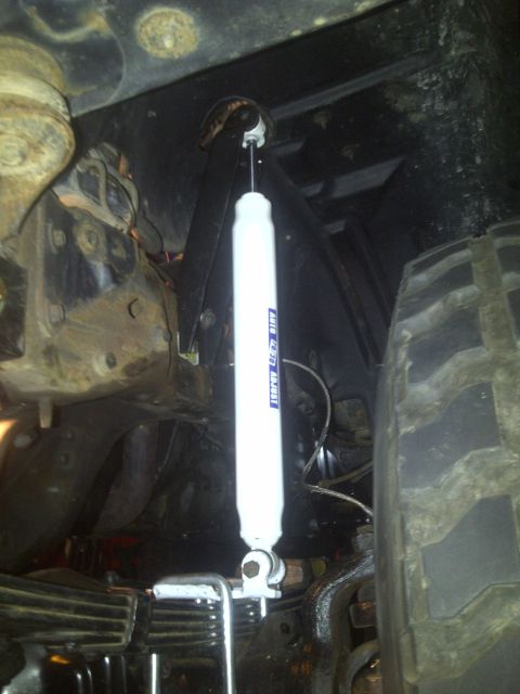 1995 Ford Bronco - A close-up view of the suspension system, including a shock absorber and tire, on a vehicle.