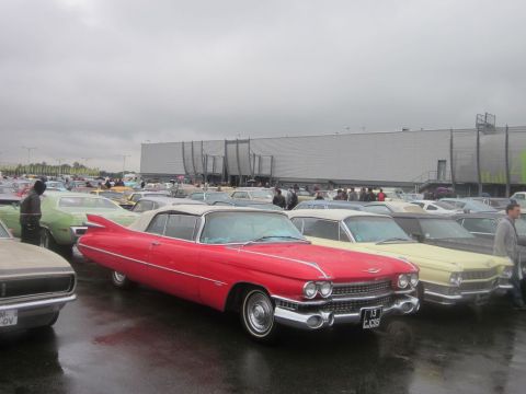 1991 Ford LTD Crown Victoria - A row of classic cars, including a red 1959 Cadillac Eldorado convertible, are parked outdoors under a cloudy sky.
