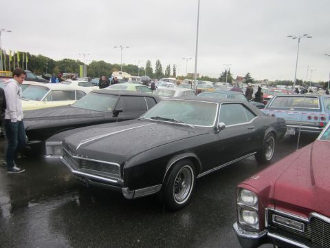 1991 Ford LTD Crown Victoria - Several classic cars are parked in an outdoor lot on a rainy day.