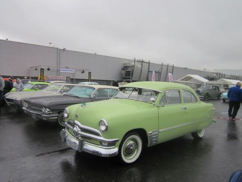 1991 Ford LTD Crown Victoria - A row of vintage cars are parked outside under a cloudy sky.