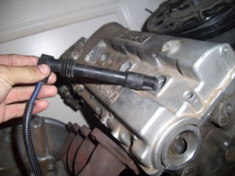 1995 Ford Probe - Close-up of a hand holding a spark plug wire near a silver engine valve cover with 'MAZDA' visible.