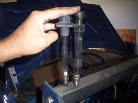 1995 Ford Probe - Two spark plug wires are held by a hand in front of an open car hood.