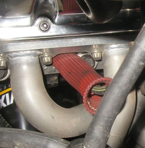 1990 Ford Bronco - Exhaust manifold pipe with a red protective heat shield covering part of it.